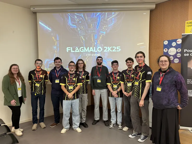 Membres du staff du Flag'Malo 2025 posant devant l'écran de l'événement