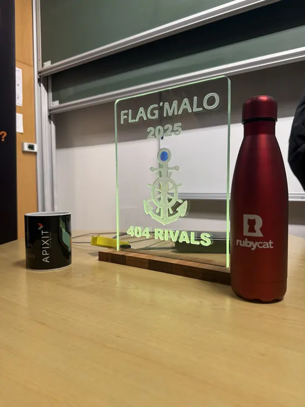 Trophée lumineux gravé Flag'Malo 2025, orné d'une ancre, posé à côté d'une gourde et d'un mug de partenaires